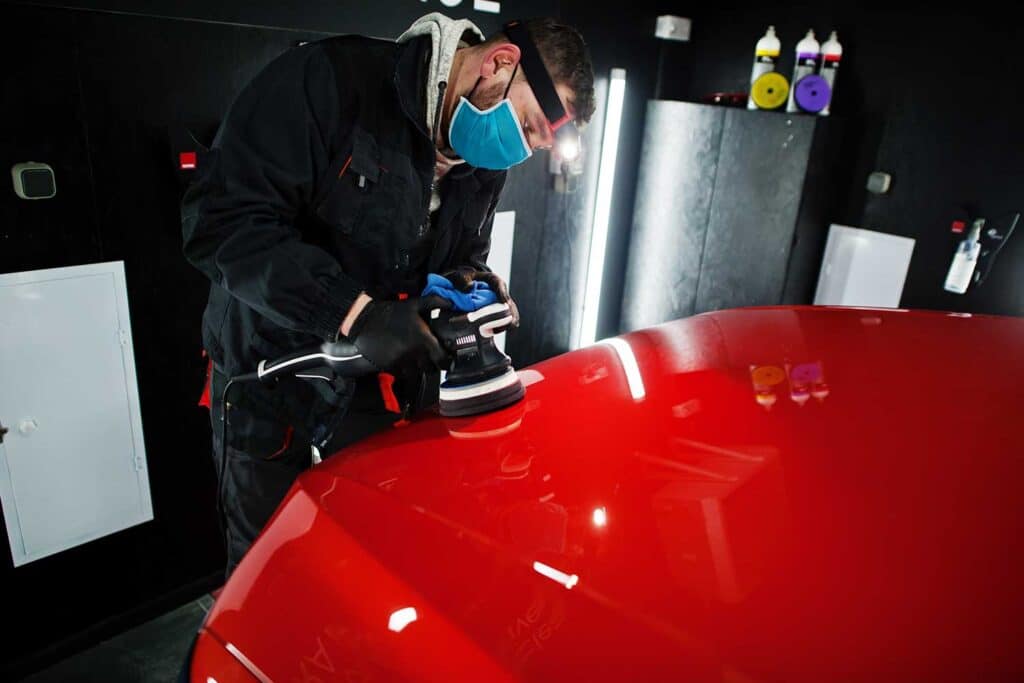 Un homme poli une voiture rouge.